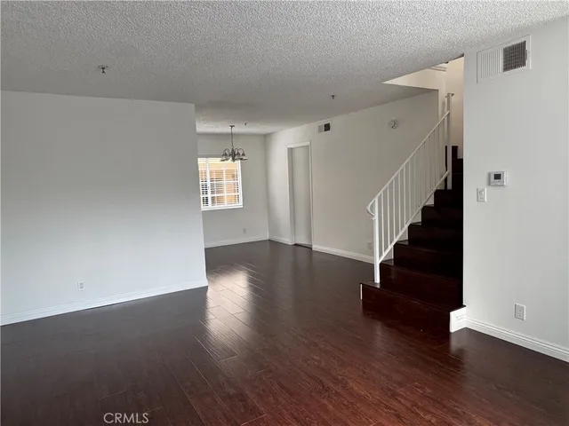 a view of an empty room with wooden floor and stairs