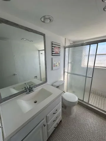 a bathroom with a sink a toilet a mirror and shower