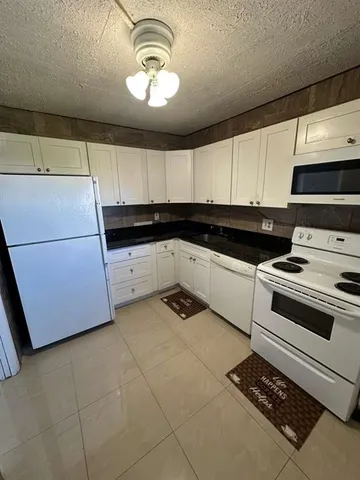 a kitchen with granite countertop a stove a sink and a microwave