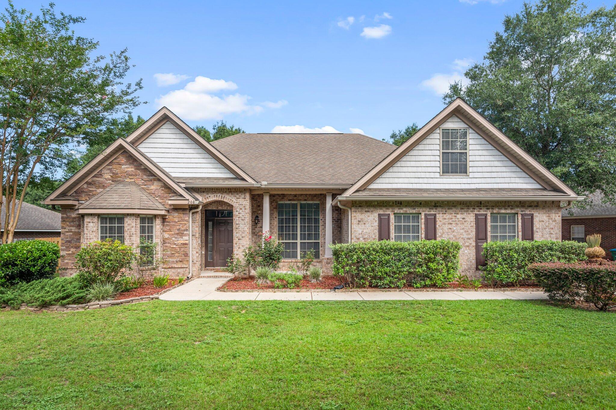 a front view of a house with a yard and green space