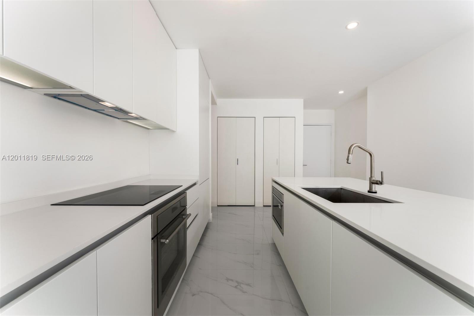 700 Northeast 24th Street, Unit 2504 Miami, FL 33137 - Photo 15 of 52 Modern chef’s kitchen equipped with custom Italian cabinetry, premium Miele appliances, integrated stone countertops, and a waterfall island perfect for entertaining.