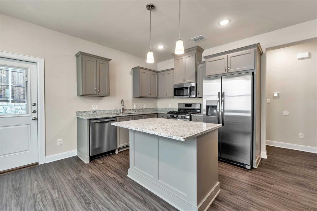 4344 Macnab Drive, Unit MULTI Tyler, TX 75707 - Photo 12 of 24 a kitchen with stainless steel appliances granite countertop a refrigerator a sink dishwasher a stove and white cabinets with wooden floor