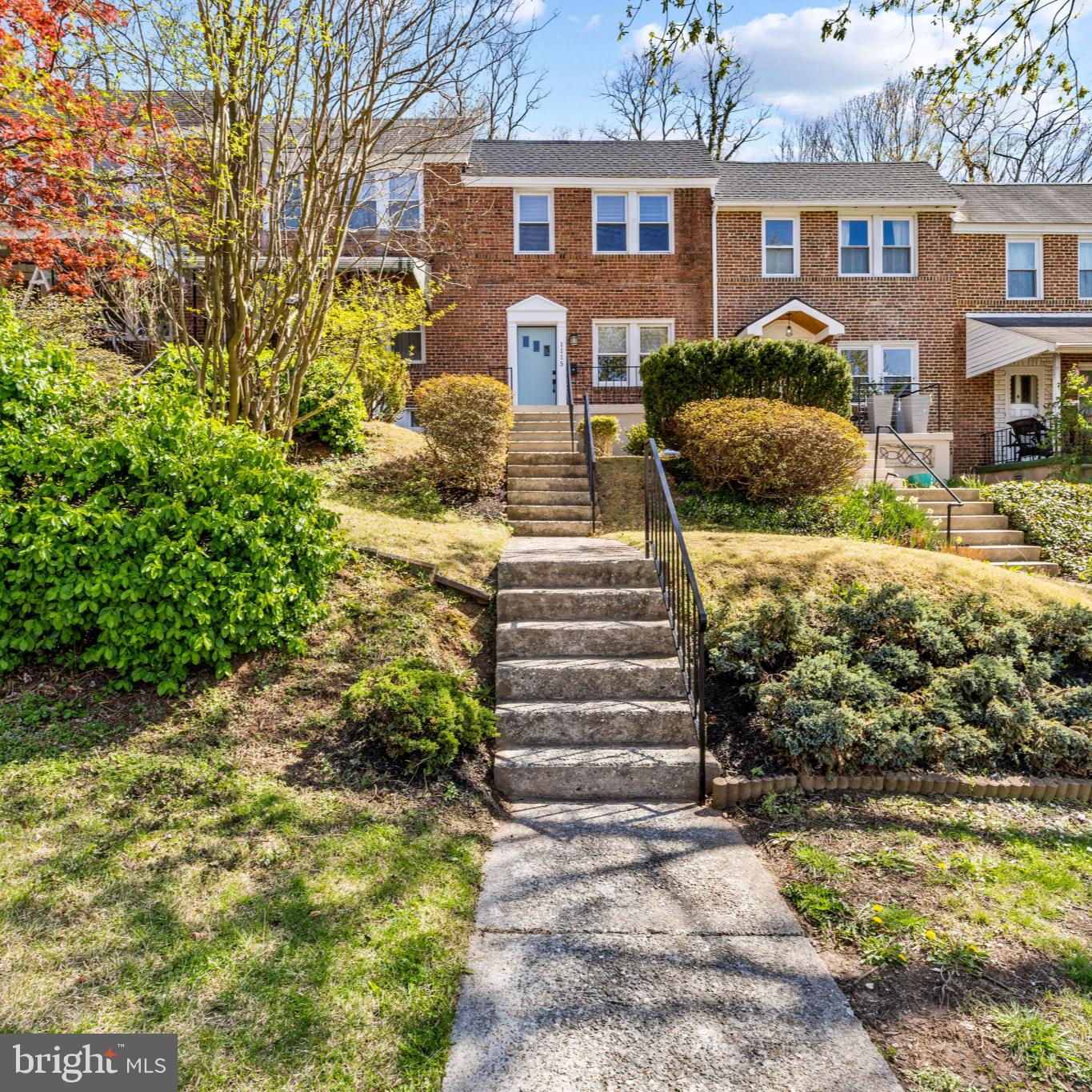 Charming brick townhouse with lush greenery.