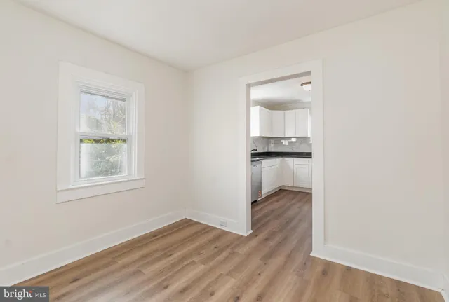 an empty room with wooden floor mirror and window