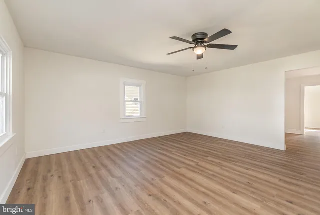 a view of empty room with wooden floor and fan