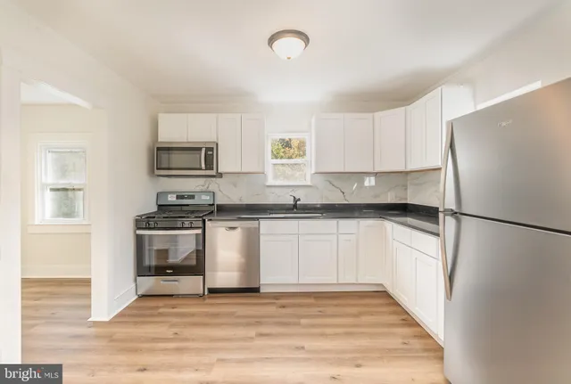 a kitchen with granite countertop a refrigerator and a stove top oven