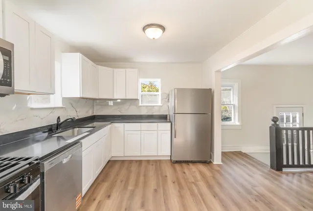a kitchen with a sink a refrigerator and white cabinets