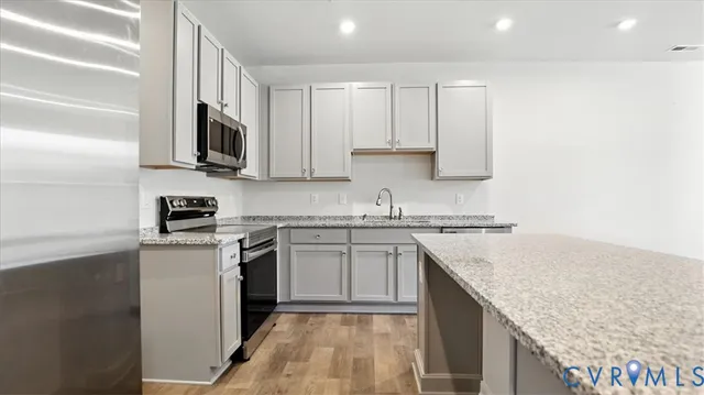 a kitchen with stainless steel appliances granite countertop a stove top oven a sink and dishwasher with white cabinets