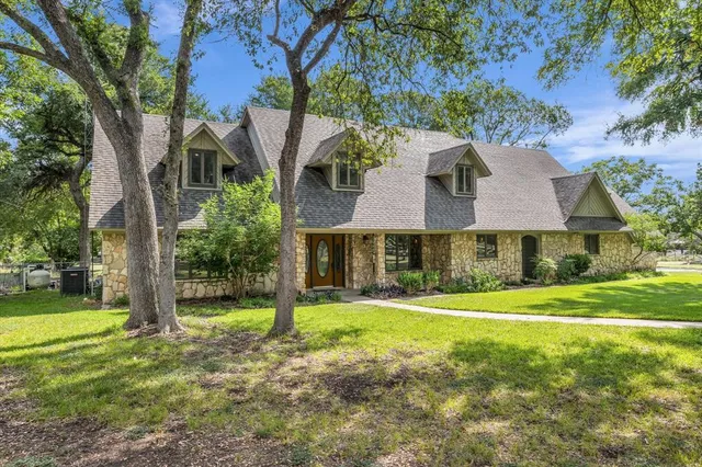 a view of a big house with a big yard and large trees