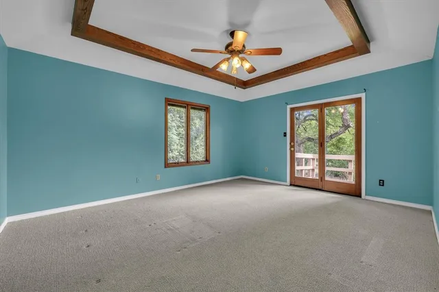 a view of an empty room with window and chandelier fan