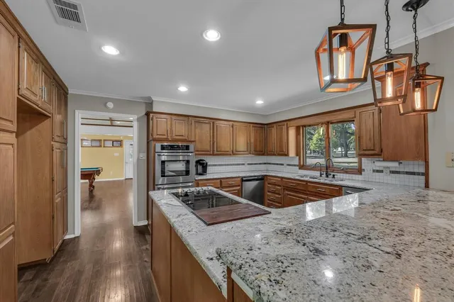 a kitchen with stainless steel appliances granite countertop a sink a stove and a refrigerator
