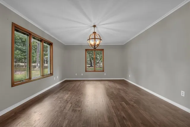 a view of an empty room with wooden floor and fan