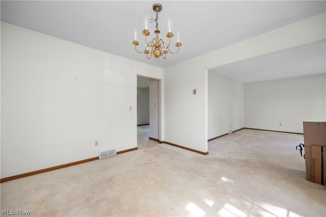 722 Jaycox Road Avon Lake, OH 44012 - Photo 17 of 48 Open-concept living space featuring a brass-tone chandelier, neutral wall paint, and light-toned carpeting