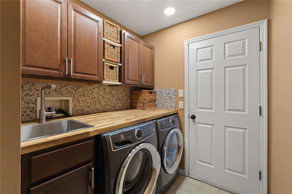 9020 North River Road Tampa, FL 33635 - Photo 22 of 86 a utility room with stainless steel appliances granite countertop a sink and cabinets with wooden floor