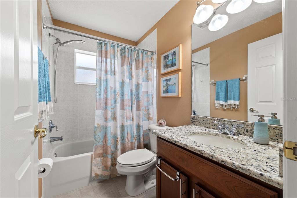 9020 North River Road Tampa, FL 33635 - Photo 34 of 86 a bathroom with a granite countertop sink a toilet a mirror and bathtub