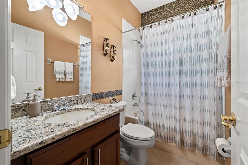 9020 North River Road Tampa, FL 33635 - Photo 39 of 86 a bathroom with a granite countertop sink a toilet and shower curtain