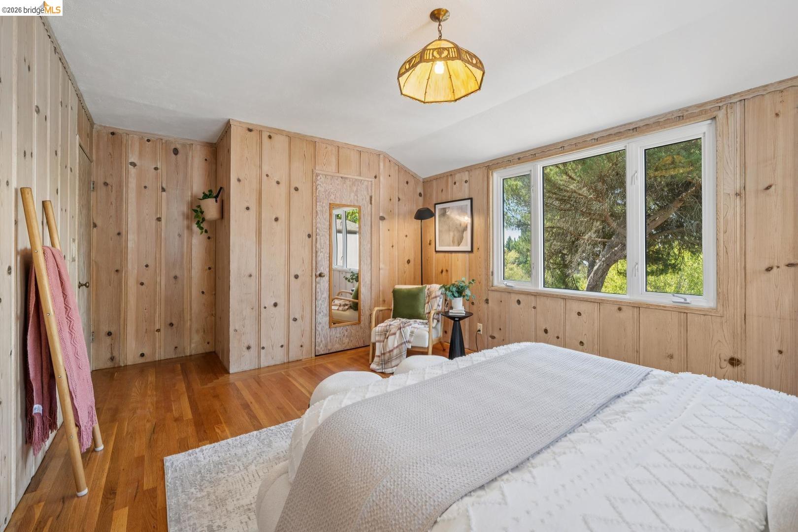 155 Avenida Drive Berkeley, CA 94708 - Photo 43 of 86 Wood-paneled walls, hardwood flooring, multiple windows, and a built-in recessed door with a mirror