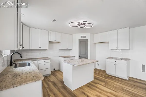 a kitchen with granite countertop a sink stove and cabinets