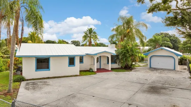a view of a house with a yard and palm trees