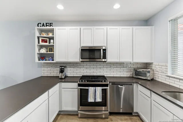 a kitchen with granite countertop white cabinets and black appliances