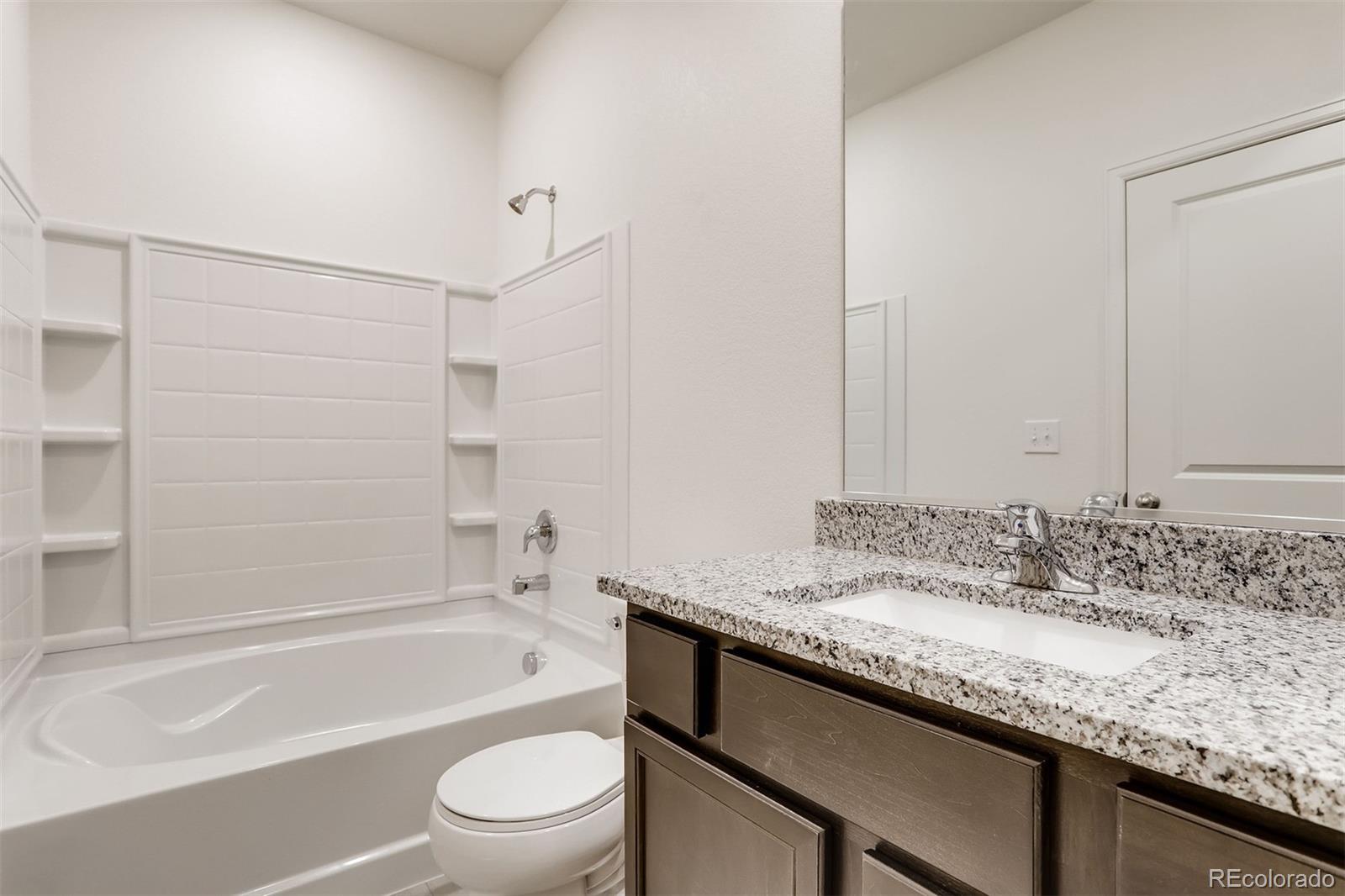 47517 Clover Avenue Bennett, CO 80102 - Photo 15 of 22 a bathroom with a granite countertop sink a toilet and bathtub