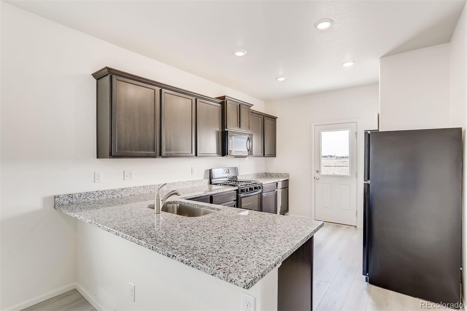 47517 Clover Avenue Bennett, CO 80102 - Photo 8 of 22 a kitchen with granite countertop a sink a refrigerator and a counter top space