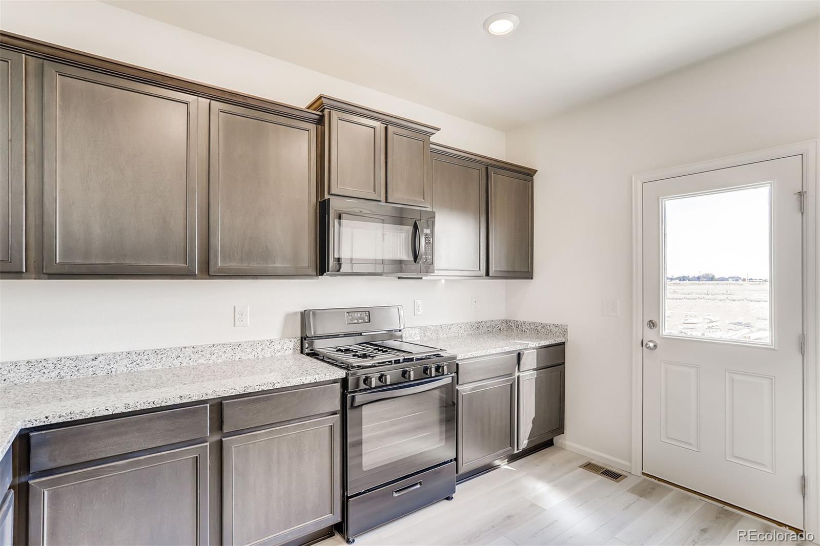 47517 Clover Avenue Bennett, CO 80102 - Photo 9 of 22 a kitchen with stainless steel appliances granite countertop a sink stove and cabinets