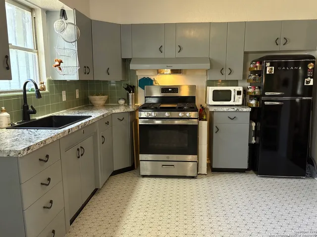 a kitchen with granite countertop white cabinets and a stove top oven
