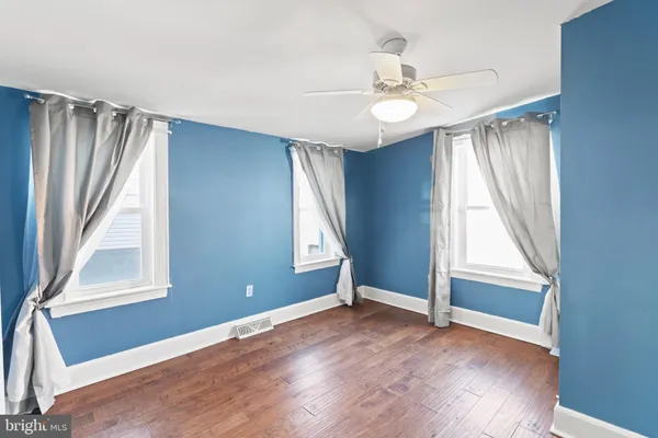 an empty room with wooden floor fan and windows
