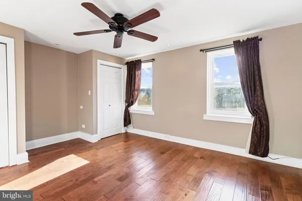 a view of an empty room with window and wooden floor