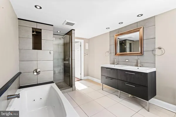 a spacious bathroom with a tub sink and mirror