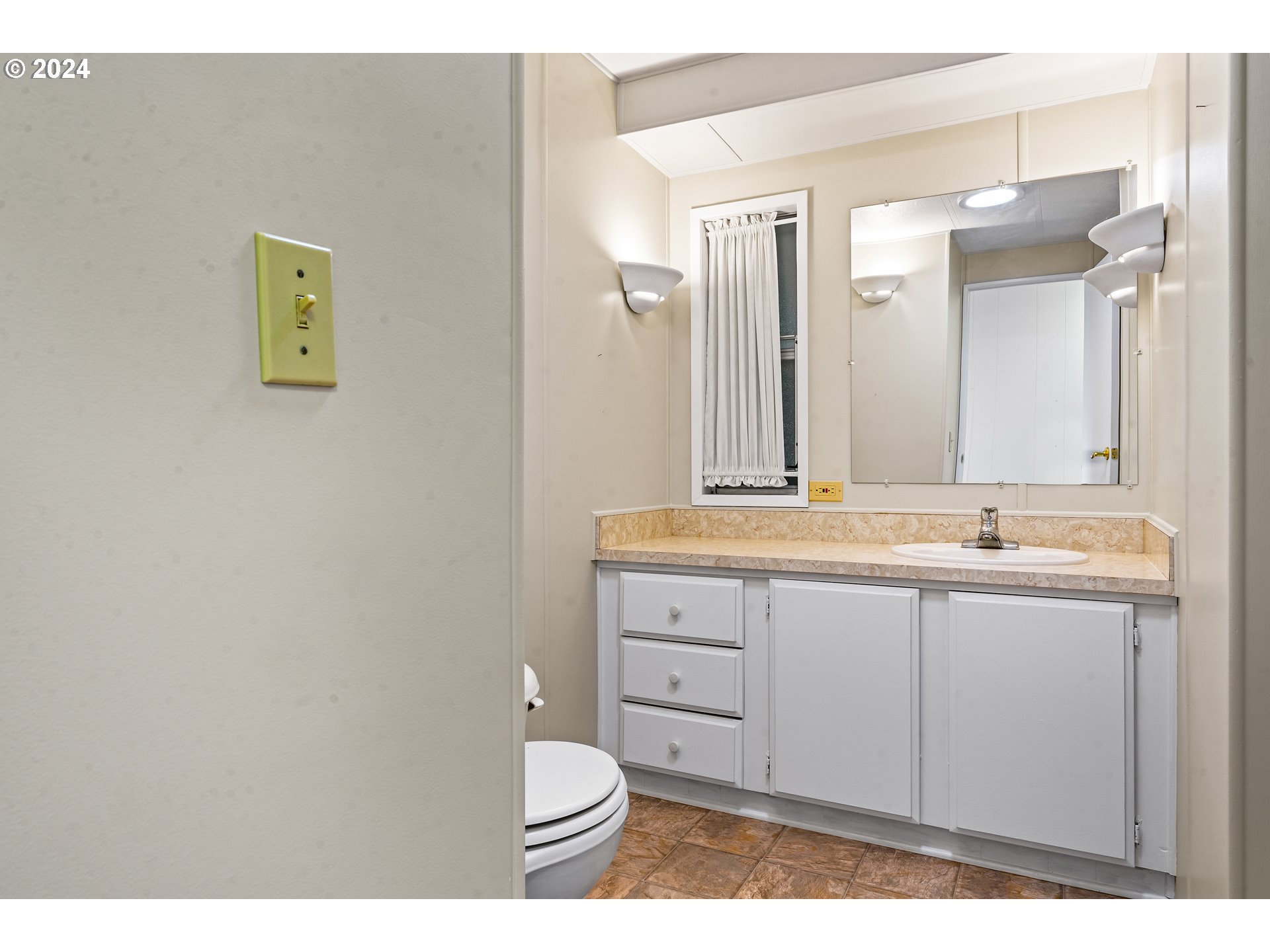 1600 Rhododendron Drive, Unit 406 Florence, OR 97439 - Photo 23 of 42 a bathroom with a granite countertop sink a toilet and a mirror
