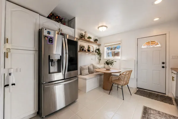 a kitchen with stainless steel appliances a refrigerator a stove a dining table and chairs with wooden floor