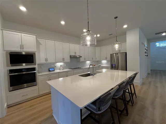 a kitchen with stainless steel appliances a dining table chairs stove and refrigerator