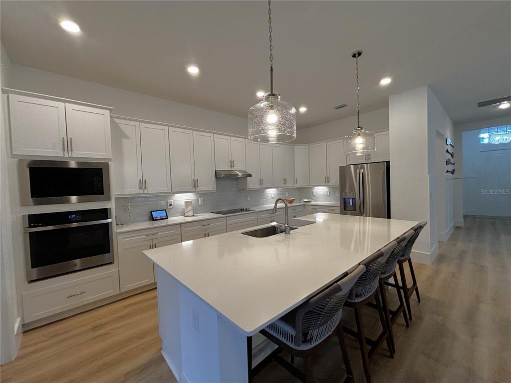 17435 Jadestone Court Venice, FL 34293 - Photo 4 of 68 a kitchen with stainless steel appliances a dining table chairs stove and refrigerator