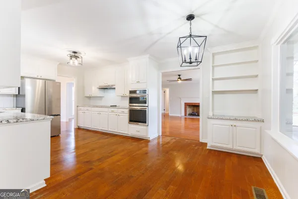 a kitchen with stainless steel appliances granite countertop a refrigerator a stove oven and white cabinets with wooden floors