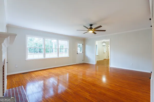 an empty room with wooden floor and windows