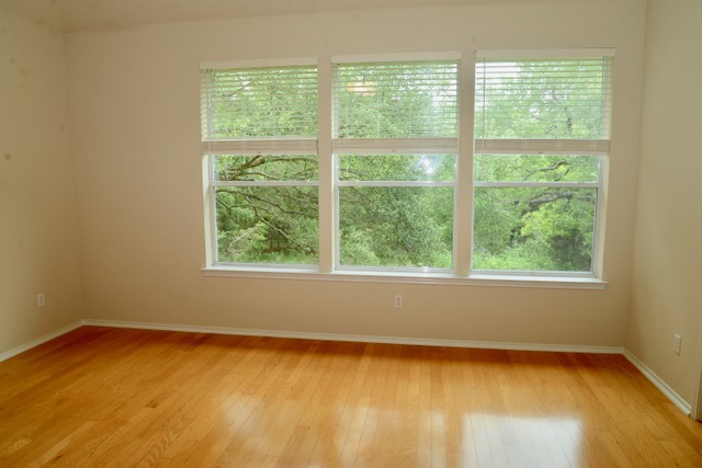 138 Chestnut Court Georgetown, TX 78633 - Photo 12 of 25 Blonde hardwood flooring and three large windows overlook a verdant, mature treeline.