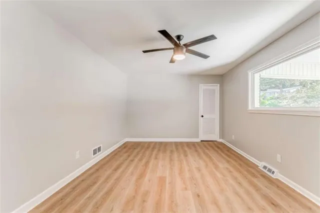 an empty room with a window and a ceiling fan