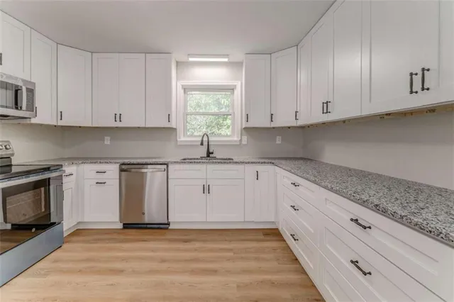 a kitchen with granite countertop white cabinets and stainless steel appliances