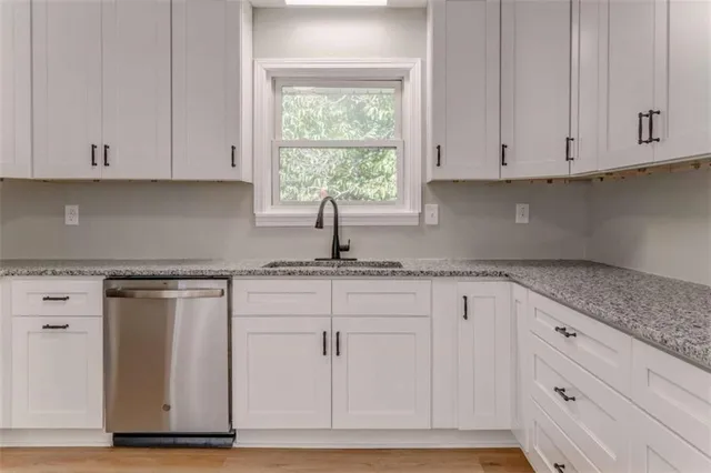 a kitchen with granite countertop white cabinets and sink