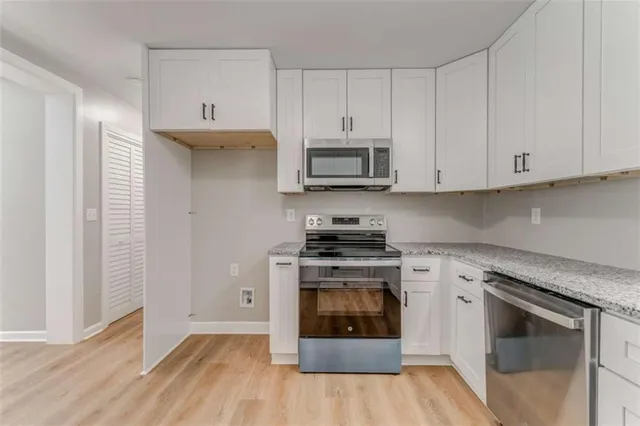 a kitchen with granite countertop white cabinets and stainless steel appliances