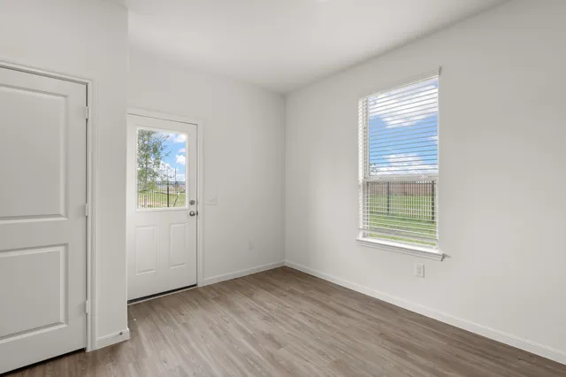 an empty room with wooden floor and windows