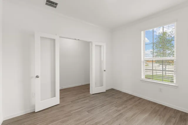 an empty room with wooden floor and windows