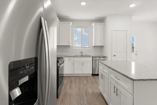 a kitchen with white cabinets and refrigerator