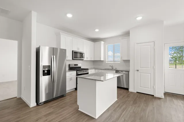 a kitchen with stainless steel appliances granite countertop a refrigerator a stove top oven a sink and dishwasher with wooden floor