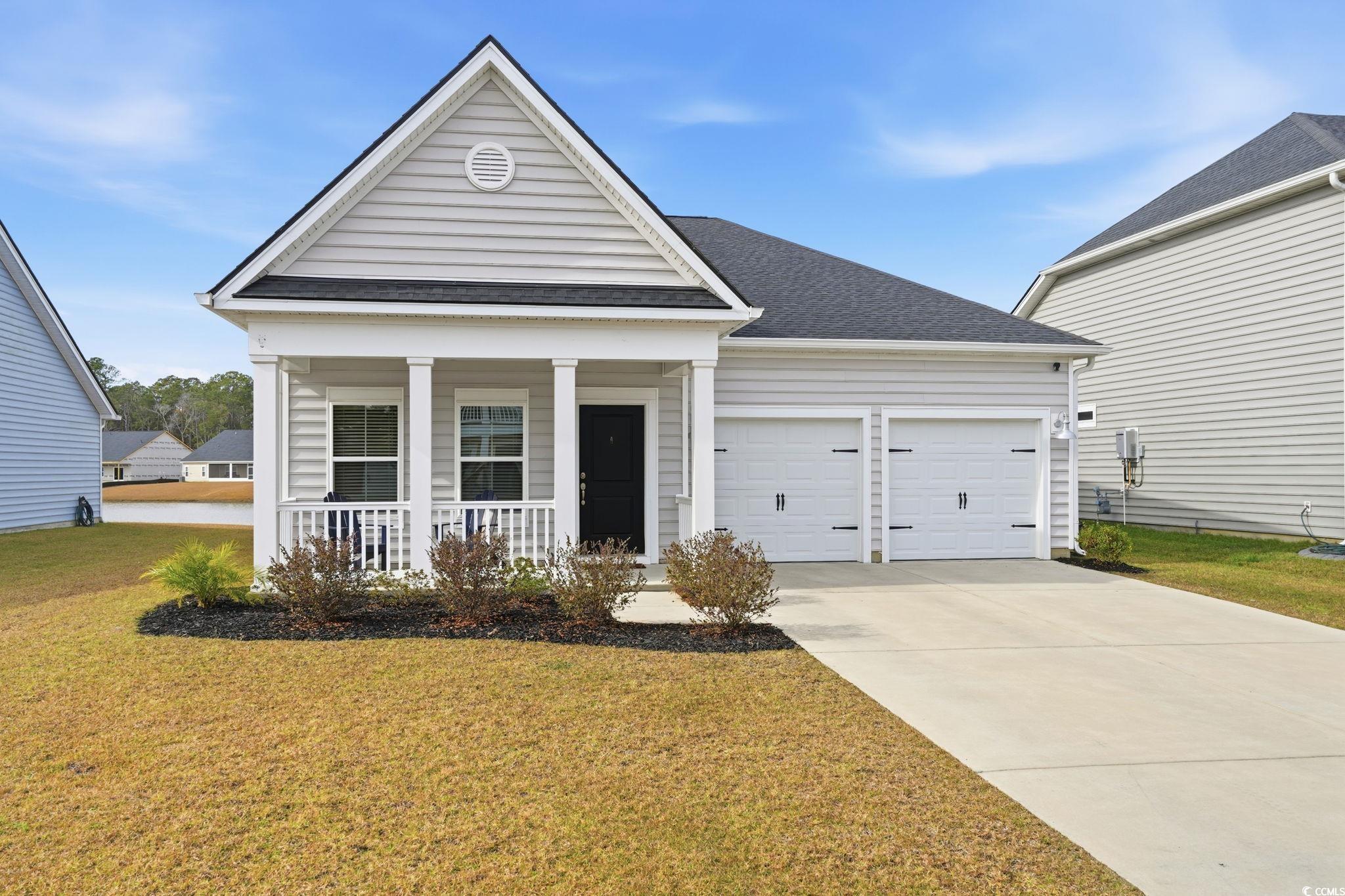176 Empyrean Circle Myrtle Beach, SC 29588 - Photo 3 of 36 View of front of home with covered porch, a front yard, driveway, an attached garage, and roof with shingles