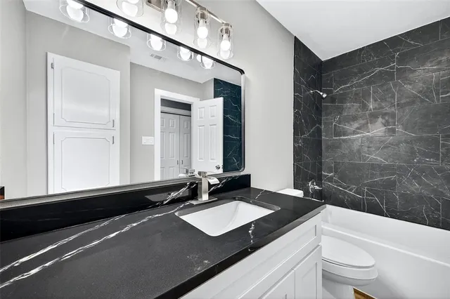 a bathroom with a sink a toilet a mirror and bathtub