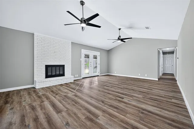 an empty room with wooden floor ceiling fan and windows