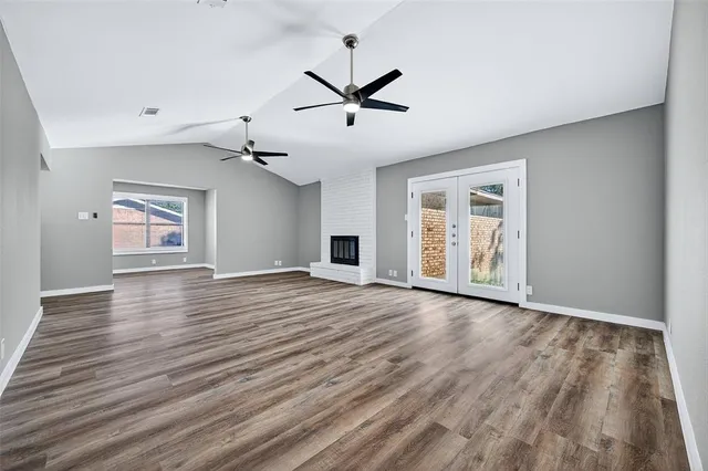 an empty room with wooden floor ceiling fan and windows